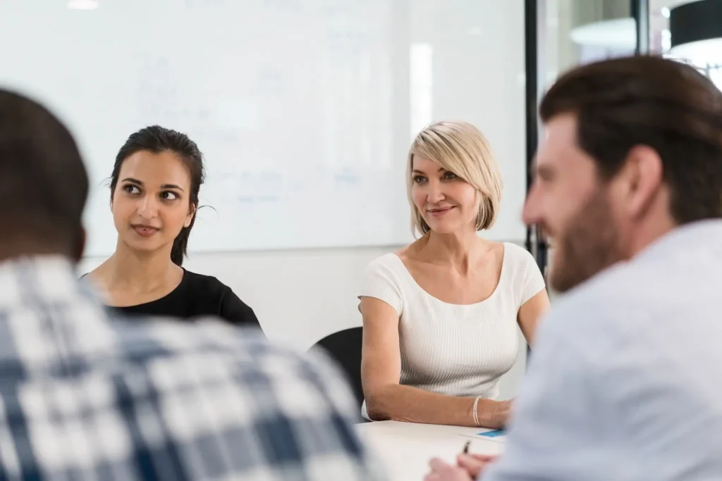 Multi-ethnic business team sitting at desk in board room. Professionals are planning during meeting. They are looking away in office.