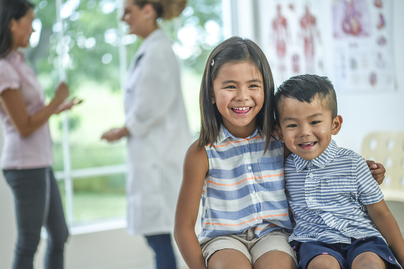 Educator and medical practitioner with happy children sitting in the foreground