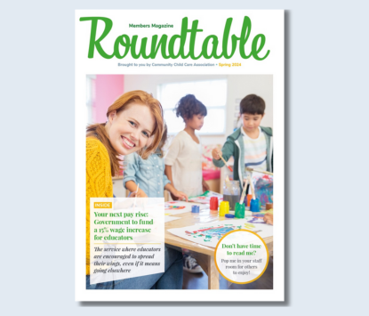 Roundtable magazine cover. Smiling educator sitting at a table with children with paints and paper