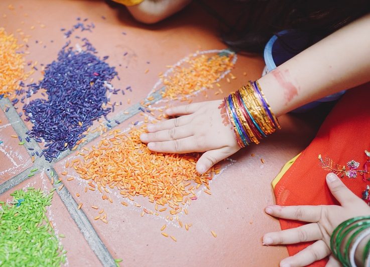 Close up on a child's hand moving coloured rice
