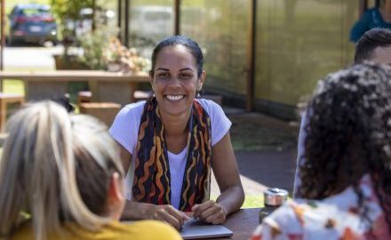 Educator sitting in an outdoor education and care setting with other educators