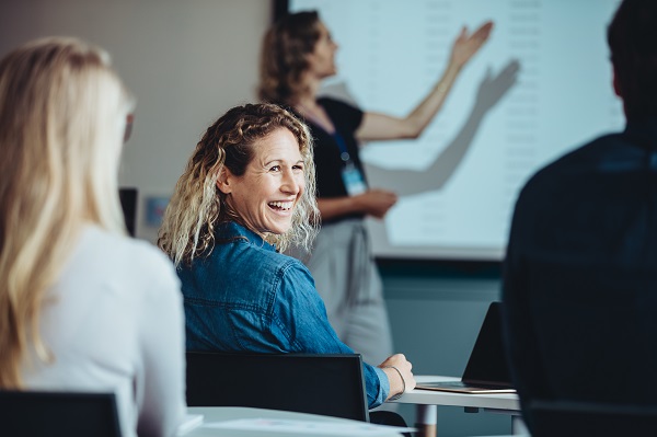 Educator at a conference, looking over her shoulder, smiling and enjoying the presentation