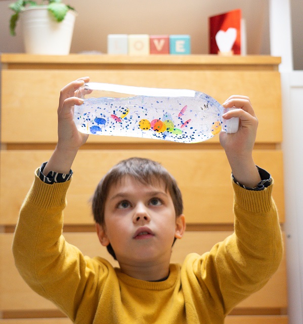 Child gazing up at sensory bottle