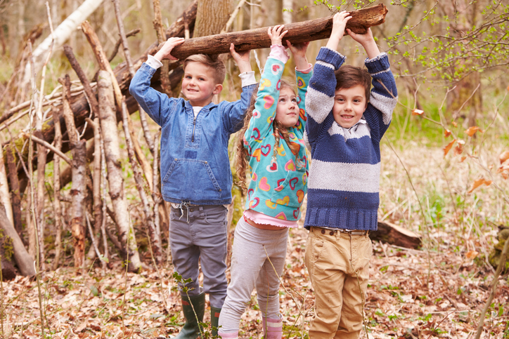 Three children playing under a tree branch
