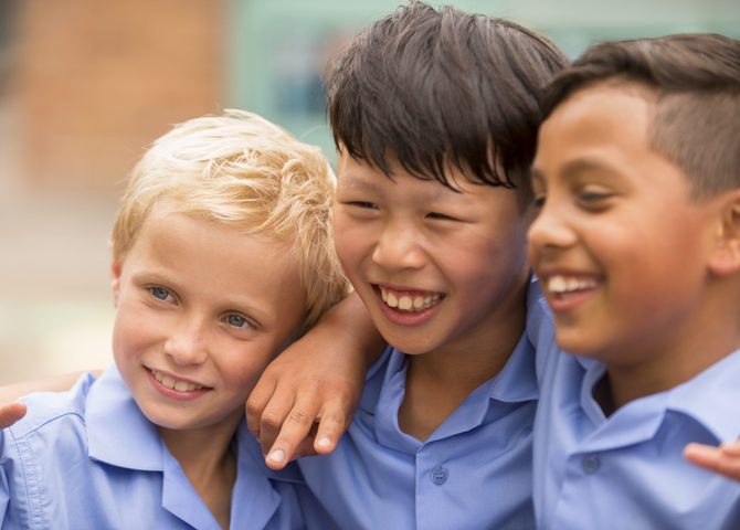 Three school children with their arms around each other's shoulders