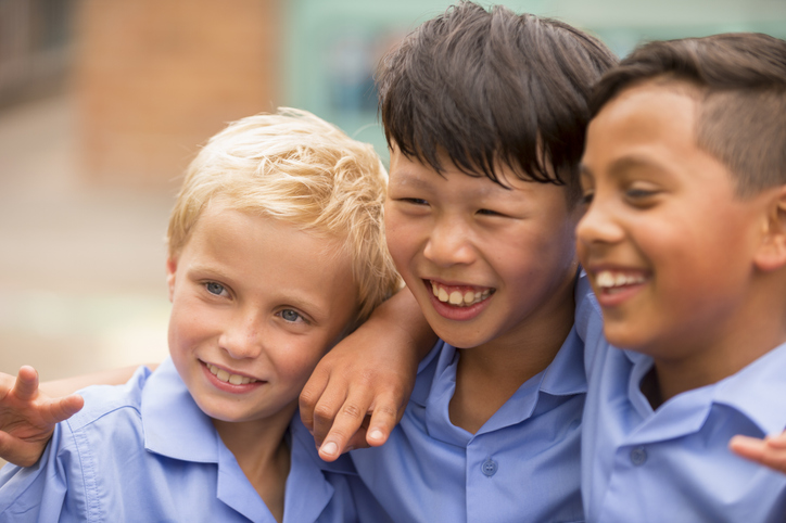 Three school children with their arms around each other's shoulders