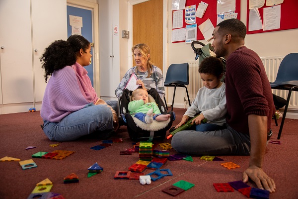Educator sitting on floor with parents and infants