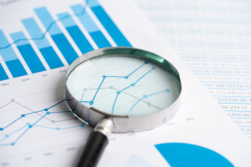 Magnifying glass resting on a document with a line graph