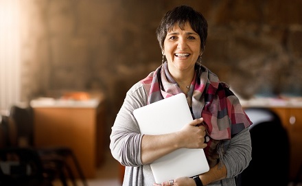 Educator holding documents and smiling at the camera