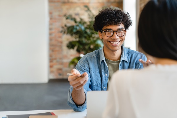 Smiling educator speaking to colleague across the table