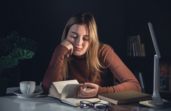 Educator sitting in the dark reading document, looking tired