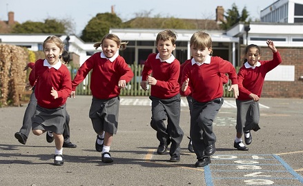 A group of children running through primary school grounds