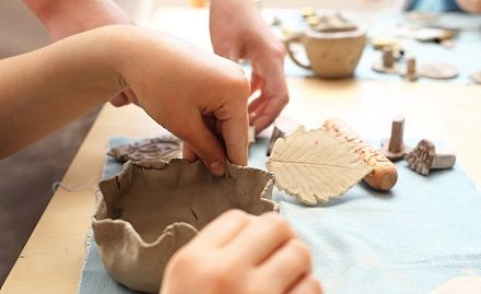 Child's hands making a small clay pot