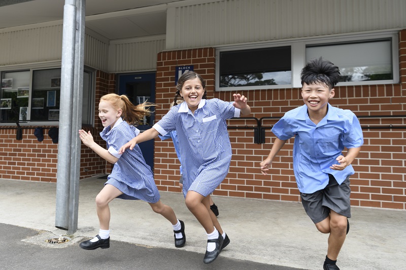 Three school age children running to the playground