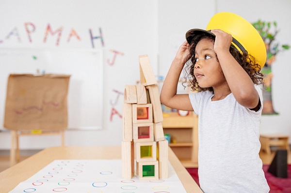 Girl trying on yellow conductor hat at education and care service