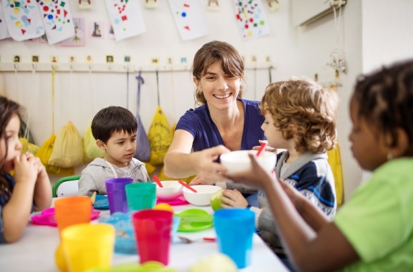 Educator passing a child their bowl during lunch