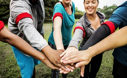 Group of people on a sporting field stacking their hands