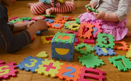 Children sitting on the floor playing with numerical cubes