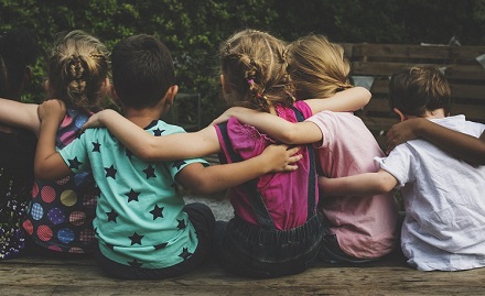 Five children with their backs to the camera arm in arm