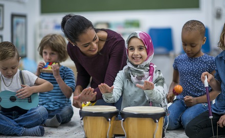 Educator playing bongo drums with children in music class