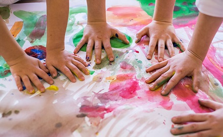 Children hands playing with paint on floor